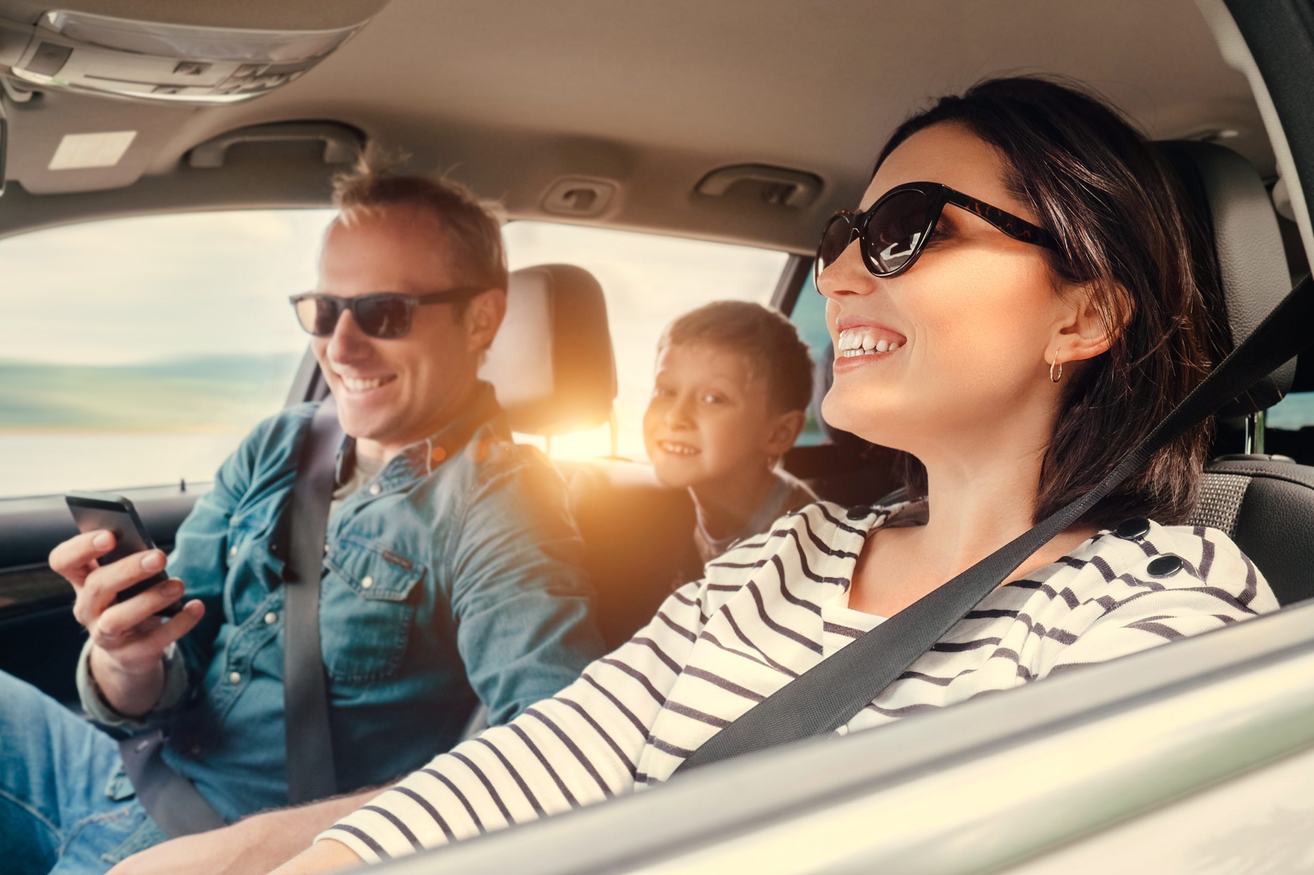 A family smiling as they drive in a car.